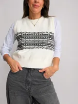 Chaleco tejido de punto con diseño de guardas geométricas en contraste, cuello redondo y terminaciones acanaladas.