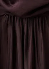 Blusa de cuello alto con detalle de fular integrado, confeccionada en tejido con textura. Presenta diseño recto, manga larga con puños abotonados y cierre posterior.