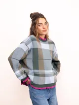 Sweater de punto con diseño de cuadros escoceses en tonos marrones y beige. Presenta un corte oversize, cuello redondo y terminaciones con volados en el cuello y los puños.
