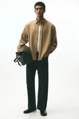 Camisa de manga larga color camel, confeccionada en sarga suave, con cuello americano y tapeta clásica con botones. Presenta canesú en la espalda y bajo redondeado.