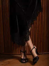 Pollera midi de terciopelo negro con corte asimétrico y detalle de encaje en el ruedo.