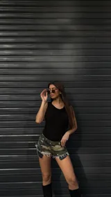 Short de jean con estampado de camuflaje en tonos verde, marrón y beige, con terminaciones desflecadas.