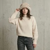 Buzo de punto con textura suave y esponjosa, color beige, con cuello media polera y puños acanalados en rib grueso.