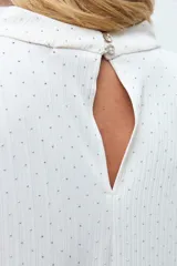 Blusa negra con pequeños puntos brillantes, cuello drapeado y mangas cortas.