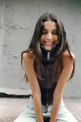 Top de punto canalé en color bordó, sin mangas y con cuello alto. Presenta un cierre frontal completo con cremallera metálica.