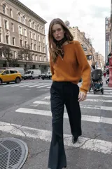 Pantalón de tiro alto color bordó, con pinzas delanteras, bolsillos frontales y falsos bolsillos con solapa en la espalda. Tiene pernera ancha y cierre frontal con cremallera, botón interior y gancho.