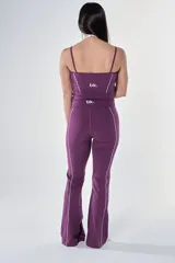 Conjunto deportivo compuesto por una musculosa de escote redondo con breteles finos y un pantalón de corte recto, ambos en color violeta con detalles de costuras blancas a contratono.