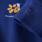 Canguro azul con capucha, cordones ajustables, bolsillo tipo canguro y puños y cintura acanalados. Estampado pequeño con una flor y letras en el pecho.