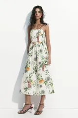 Vestido midi de color blanco con estampado botánico de frutas y flores, escote cuadrado, breteles finos y falda con vuelo.