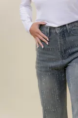 Jean de denim gris con calce ancho (wide leg) y tiro medio-alto. Presenta un detalle sutil de strass a lo largo de la tela.