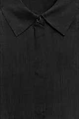 Camisa amplia confeccionada en hilatura con lyocell y ramio, color celeste, con cuello solapa, manga por debajo del codo, detalle de pliegue en la espalda y cierre frontal con botones ocultos por solapa.