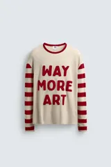 Camiseta de manga larga con cuello redondo, cuerpo color beige claro y mangas a rayas horizontales rojas y beige. Presenta texto frontal en relieve color rojo que dice "WAY MORE ART".