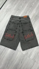 Bermuda de jean gris con bolsillos traseros y delanteros, con bordado de llamas rojas en los bolsillos delanteros.