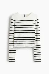 Buzo corto de punto suave, color blanco con rayas horizontales negras. Tiene cuello redondo y bajo recto.