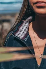 Buzo de algodón con efecto lavado, cuello alto con medio cierre frontal, mangas largas y corte holgado. Presenta un estampado gráfico en el pecho con la inscripción 'Glassy Waves'.