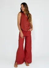 Pantalon de corte recto y pierna ancha, confeccionado en lino color beige. Presenta un diseño de tiro medio con aberturas laterales en el ruedo y detalle de bordes desflecados.