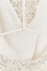 Top blanco con lentejuelas plateadas, de cuello halter y espalda descubierta.