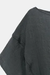 Camisa amplia de color rosado, con diseño estilo capa, cuello redondo y manga corta amplia. Cuenta con un bajo ajustable mediante lazada lateral.