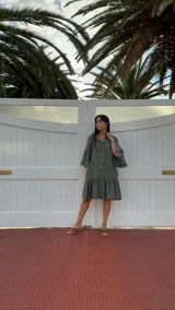 Vestido corto color verde militar, con cuello mao, botones frontales, mangas cortas acampanadas y volados en el ruedo. Confeccionado en lino. Fabricado en Italia.