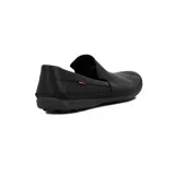 Zapato tipo mocasín o náutico de hombre, color negro, con costura artesanal visible alrededor del empeine y puntera. Presenta perforaciones tipo picado en la parte frontal y un pequeño detalle de etiqueta roja en el lateral.