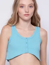 Top blanco de tela texturada, sin mangas y con cuello redondo. Cuenta con cuatro botones y terminación en curva en la parte delantera.