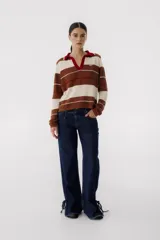 Pantalón de jean azul oscuro de corte recto, con cintura alta con cinturón del mismo material y detalle de flecos en la cintura y en los tobillos.