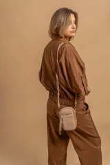 Bandolera compacta color rosado, con correa regulable y desmontable. Tiene apertura superior, bolsillo frontal con cierre y detalle de borla, y bolsillo trasero sin cierre. El interior está forrado en tela y cuenta con un bolsillo adicional.