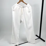 Pantalón blanco de muselina, corte recto, con bolsillos delanteros y traseros, cintura elastizada con cordón de ajuste.