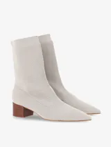 Bota tipo media de punto color beige con caña media, punta fina y taco cuadrado de madera de altura baja.