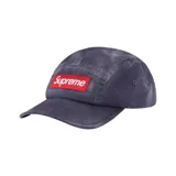 Gorro tipo camp cap de Supreme, con diseño de cinco paneles y acabado desgastado. Presenta el logo de la marca en un parche rectangular rojo con letras blancas en la parte frontal.