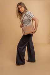 Bandolera de diseño práctico con combinación de texturas en tonos tierra, confeccionada en tela y símil cuero. Cuenta con un compartimento principal con cierre, un bolsillo frontal con cierre y correa ajustable para llevar al hombro o cruzada.