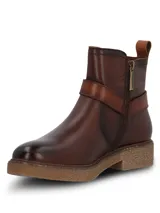 Botines de cuero color marrón oscuro, con diseño de caña media, cierre lateral y una tira decorativa con hebilla metálica sobre el empeine. Presentan una suela de goma texturizada en tono natural y un pequeño logo metálico en la parte superior de la caña.