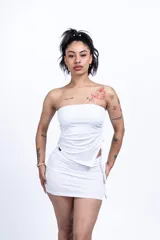 Mini vestido blanco de corte ajustado, compuesto por un top tubo con frunce lateral y una minifalda.