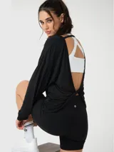 Remera de manga larga con cuello redondo, confeccionada en tejido modal suave con acabado de Aloe Vera. Presenta un diseño de espalda abierta con detalle de nudo twist-back, ofreciendo un calce holgado y cómodo.