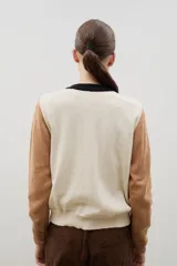 Saco de punto con diseño color block, presenta cuerpo en color bordó, mangas en color rojo y tapeta frontal con cuello redondo en color rosado. Posee cierre frontal con botones y puños acanalados.