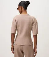 Blusa Cortelle de modal color beige, con corte peplum, cuello redondo, mangas cortas y recortes estruturados que marcan la cintura.