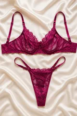 Conjunto de lencería de dos piezas en color fucsia, confeccionado en encaje floral. Incluye un corpiño con aro y tirantes regulables, y una tanga regulable con tiras dobles en los laterales.
