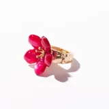 Anillo dorado con banda elástica y aplique de flor fucsia de resina.