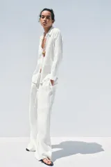 Camisa color coral confeccionada en lino 100%, de corte recto, con cuello solapa, manga larga con puños abotonados y cierre frontal con botones.