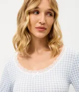 Blusa de pijama de manga larga con estampado de cuadros vichy en tonos celestes y blancos. Presenta un cuello redondo decorado con encaje delicado y un corte regular cómodo.