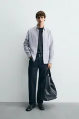 Camisa de corte regular fit confeccionada en tejido de algodón con diseño de rayas verticales. Presenta cuello abotonado, manga larga con puños abotonados y cierre frontal de botones.