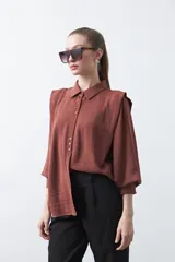 Camisa negra de estilo sastrero con cuello clásico, frente abotonado y mangas largas con puños ajustados. Presenta un diseño con hombreras sutiles que aportan estructura a la prenda.