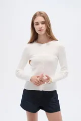 Remera de manga larga al cuerpo confeccionada en viscosa, de color blanco, con cuello a la base y cierre frontal de botones.