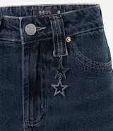 Pantalón de jean corte baggy con cintura media, diseño de cinco bolsillos y cierre frontal con cremallera y botón. Presenta un lavado oscuro sobretinta y una trabilla con colgante metálico desmontable.