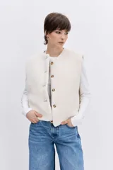 Chaleco reversible de diseño acolchado con costuras en rombos, color tostado con interior de corderito blanco. Presenta cierre frontal con botones, cuello redondo y bolsillos delanteros.