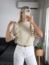 Blusa de símil lino color beige, con cuello redondo fruncido, doble volado en los hombros con detalle de encaje y manga 3/4.