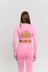 Conjunto deportivo de dos piezas compuesto por un top de manga larga con cuello redondo y detalle de tejido calado en el pecho, y calzas de tiro alto. Ambas prendas presentan un diseño sin costuras en un tono rosado vibrante.