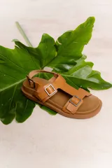 Sandalias negras con doble hebilla ajustable en la parte superior y una hebilla en la correa del tobillo. Tienen plantilla anatómica y suela liviana y flexible.