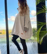 Canguro gris claro con cuello alto, mangas largas con puños en gris oscuro, bolsillo tipo canguro y corte holgado.