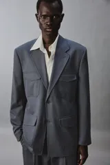 Blazer de corte regular confeccionada en tejido con lana, con cuello de solapas de muesca y manga larga con puños abotonados. Presenta cierre frontal de botonadura y cuatro bolsillos plastrón con solapa en el delantero.